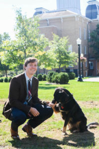 New Assistant Professor of Philosophy Blake Mcallister pets his German shepherd mix, Reid, on the Quad. Hannah Kwapisz | Collegian 