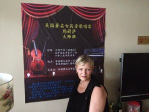 Hillsdale voice instructor Melissa Osmond stands before a poster advertising her performance in Guanzhou, China, this past summer.                Melissa Osmond  | Courtesy